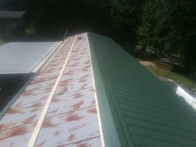 Old rusted panels beside newly installed green metal roofing — Wind Damage Roof Repair by Roofing Brothers in Dwight