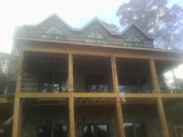 Dormers and porch framing on a large log home under construction — Roof Coating work by our crew in Dwight